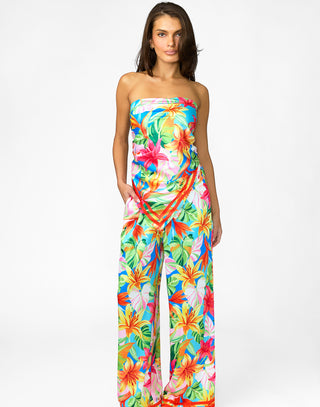 Woman wearing a colorful strapless jumpsuit with a floral pattern on a white background