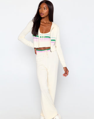 Woman wearing a white cardigan, colorful top, and pants on a white background