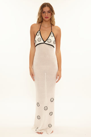 Woman wearing a white dress with black floral embroidery on a white background