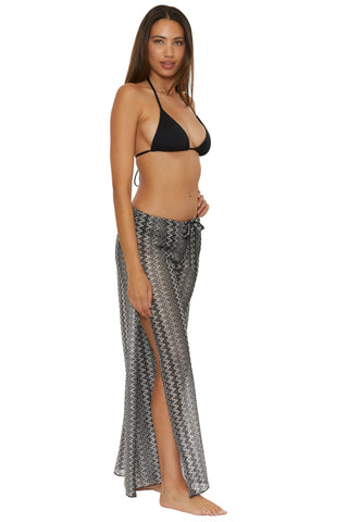 Woman wearing a black bikini top and patterned sarong on a white background