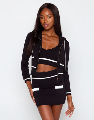 Woman wearing a black and white outfit with a jacket and skirt on a white background