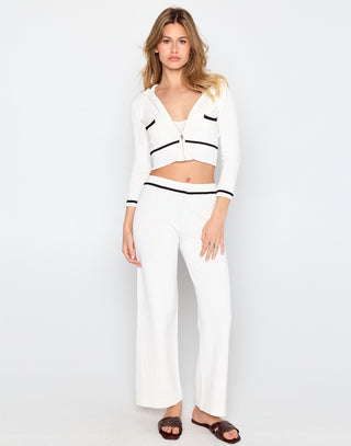 Woman wearing a white outfit with black accents on a white background