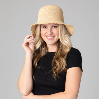 Model wearing a tan crochet bucket hat with a scalloped brim. 