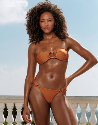 Woman wearing an orange bikini set with a clear sky background