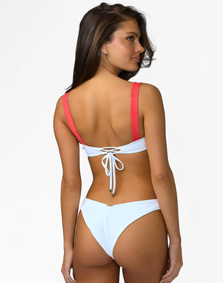 Woman wearing a white bikini with red straps on a white background